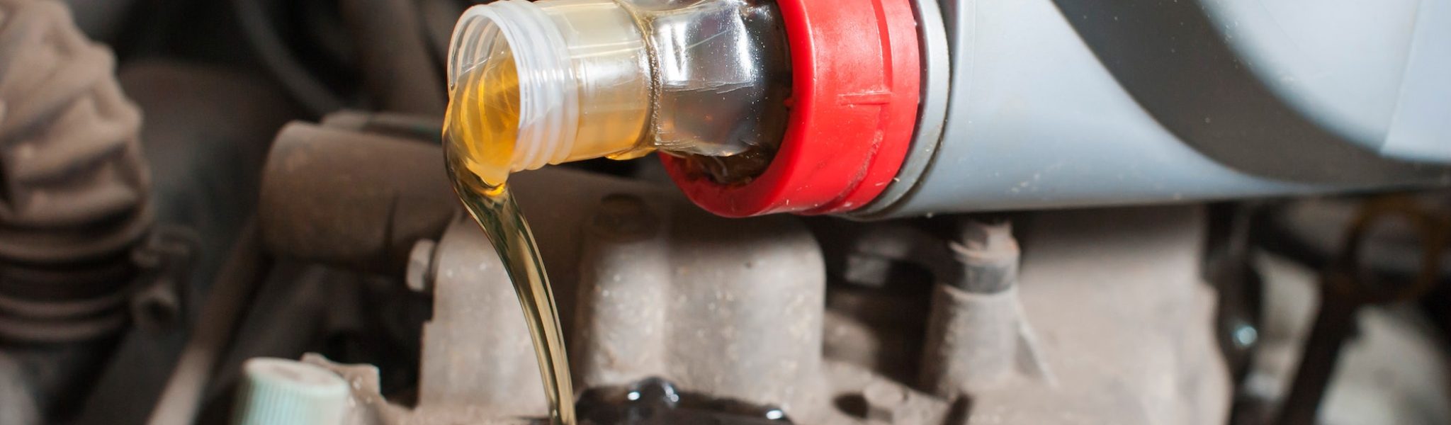 a man pours oil into a car engine close-up